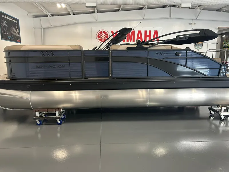 Slide: The Image of 2025 Bennington 22 SXSB pontoon boat displayed indoors at Yamaha dealership. - 2