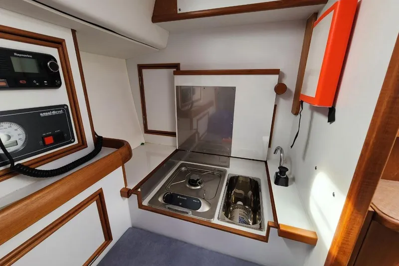 Slide: The Image of 2017 Rustler 33 yacht interior with compact kitchen, stove, and sink. - 5