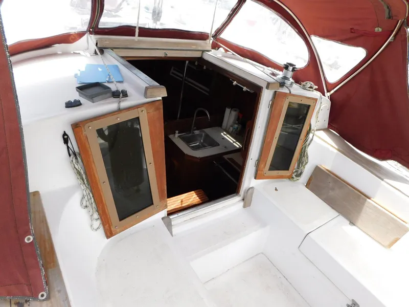 Slide: The Image of 1984 Endeavour 35.5 Sloop cockpit with open hatch, red canopy, and visible interior sink. - 19
