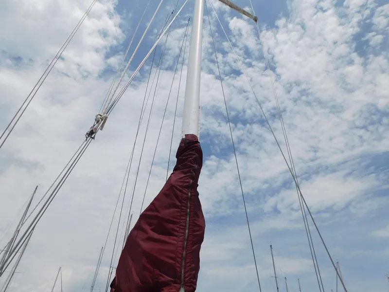 Slide: The Image of 1984 Endeavour 35.5 Sloop mast with maroon sail cover against cloudy sky. - 27