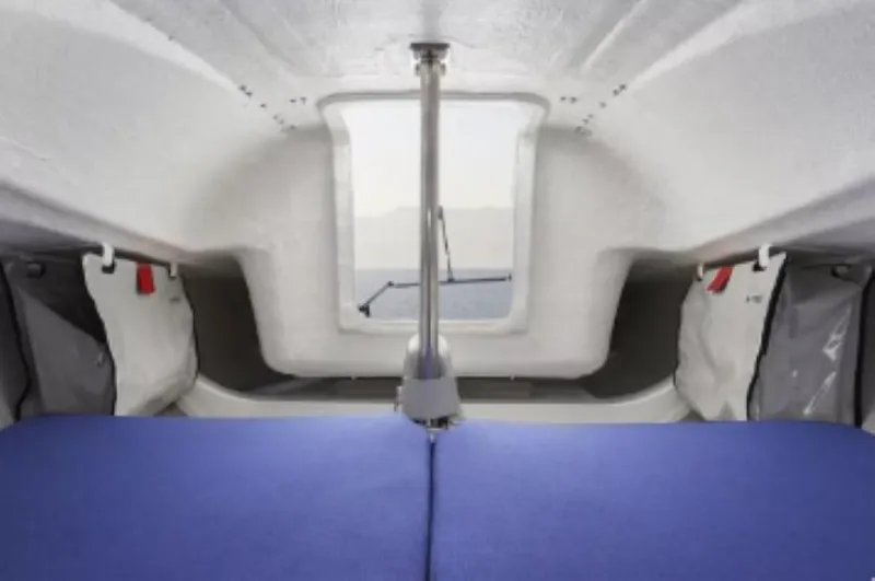 Slide: The Image of Interior cabin of 2025 Beneteau First 18 SE sailboat, featuring compact design and blue seating. - 8