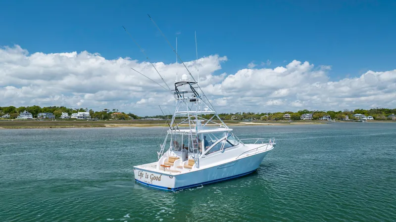 Slide: The Image of 2013 Viking 42 boat cruising on a calm, scenic waterway under a partly cloudy sky. - 11