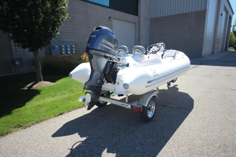 Slide: The Image of 2025 Zodiac Yachtline 400 DL NEO with 50hp engine on trailer, parked outdoors. - 2