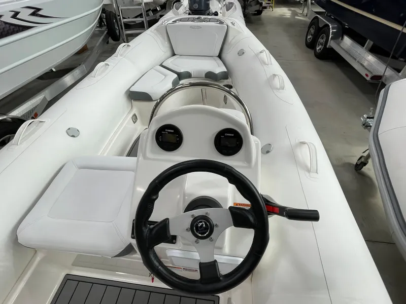 Slide: The Image of 2025 Zodiac Yachtline 490 Deluxe NEO, sleek white interior, steering wheel, and seating. - 28