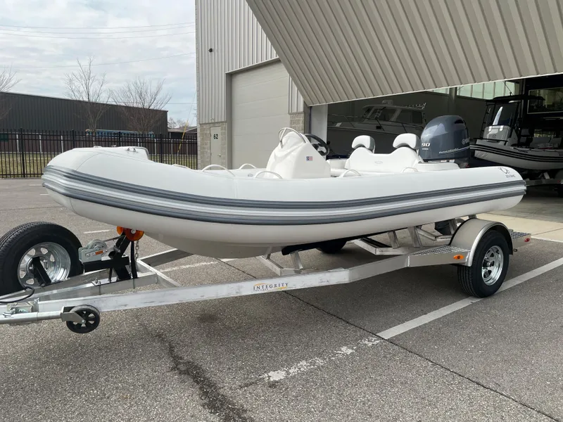 Slide: The Image of 2025 Zodiac Yachtline 490 Deluxe NEO 90hp on trailer, parked outside a building. - 6