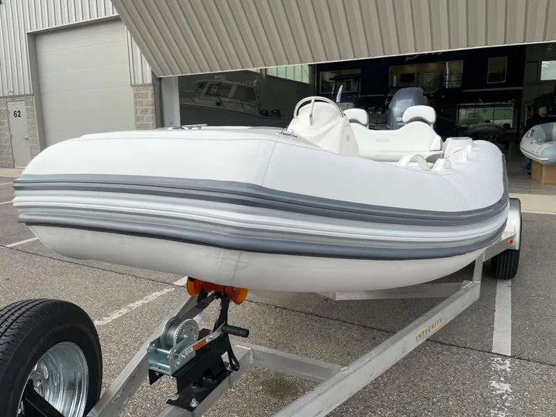 Slide: The Image of 2025 Zodiac Yachtline 490 Deluxe NEO 90hp on trailer, parked outside a building. - 7