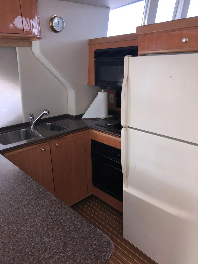 Slide: The Image of 2002 Bayliner 5288 PILOTHOUSE kitchen with wooden cabinets, sink, and refrigerator. - 16