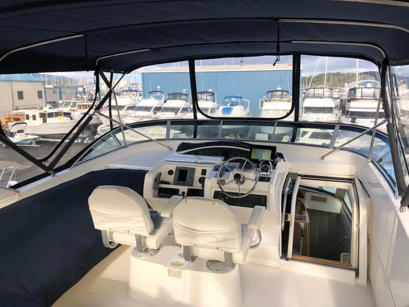 Slide: The Image of 2002 Bayliner 5288 Pilothouse interior with helm, seats, and marina view. - 7