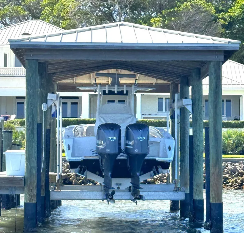 Slide: The Image of 2012 Jupiter 34 FS boat with twin Yamaha engines on a lift by waterfront home. - 49