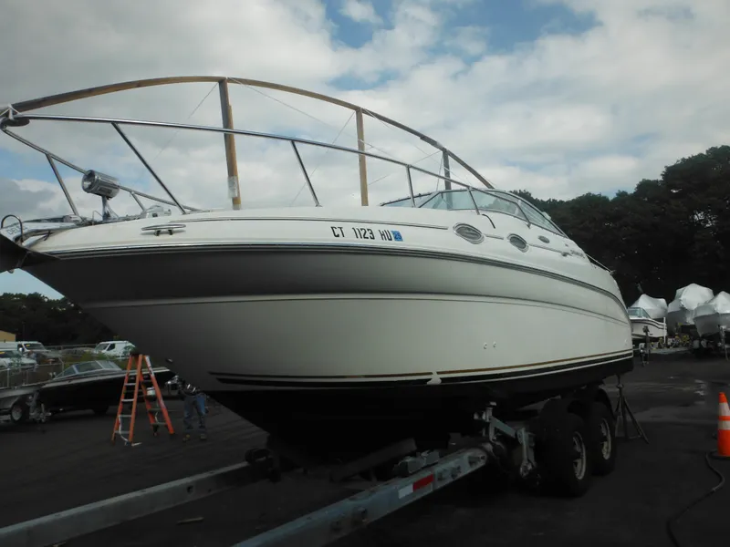 Slide: The Image of 2002 Sea Ray 260 Sundancer boat on trailer, parked outdoors under cloudy sky. - 12