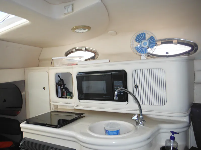 Slide: The Image of 2002 Sea Ray 260 Sundancer cabin kitchen with microwave, sink, and fan. - 44