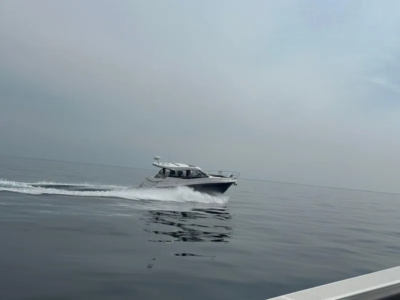 The Image of 2025 Regal 38 Grande Coupe docked at a marina, surrounded by other boats. - 0
