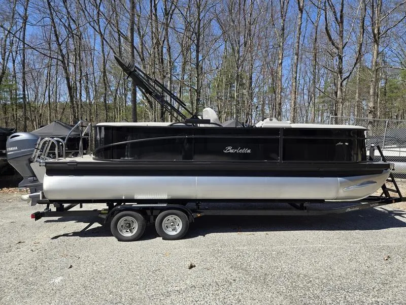 Slide: The Image of 2025 Barletta A22QC pontoon boat on trailer, parked in wooded area. - 3
