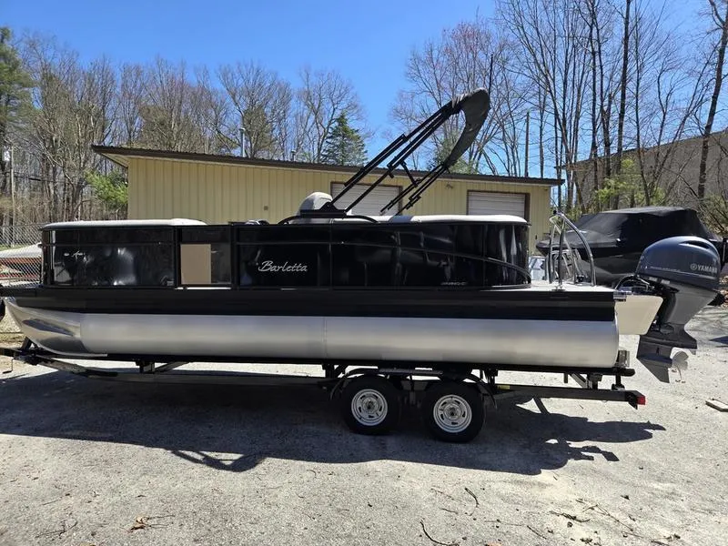 Slide: The Image of 2025 Barletta A22QC pontoon boat on trailer, parked outdoors near a building. - 4