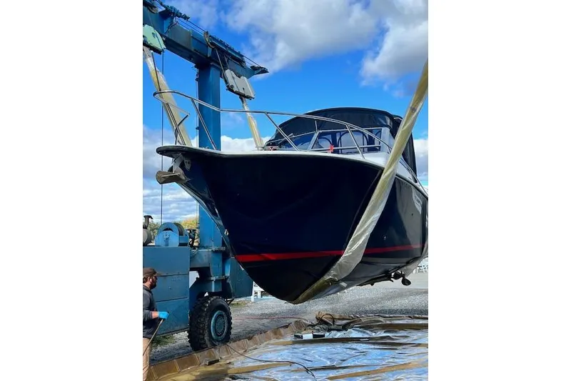 Slide: The Image of 1996 Albemarle 27 Express boat being lifted by a crane under a blue sky. - 56