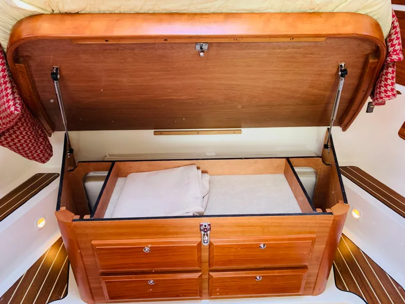 Slide: The Image of 2015 Back Cove 34 Express cabin storage with open wooden compartment and bedding. - 16