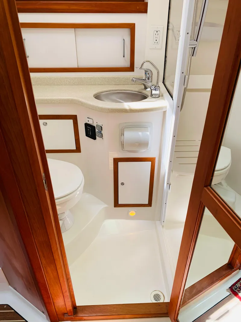Slide: The Image of 2015 Back Cove 34 Express bathroom with sink, toilet, and wooden cabinetry. - 24