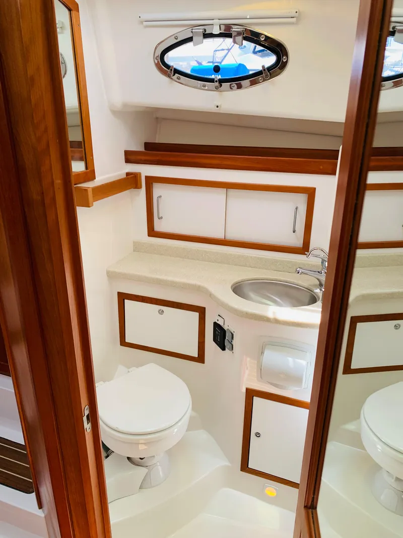 Slide: The Image of 2015 Back Cove 34 Express yacht bathroom with sink, toilet, and wooden accents. - 25