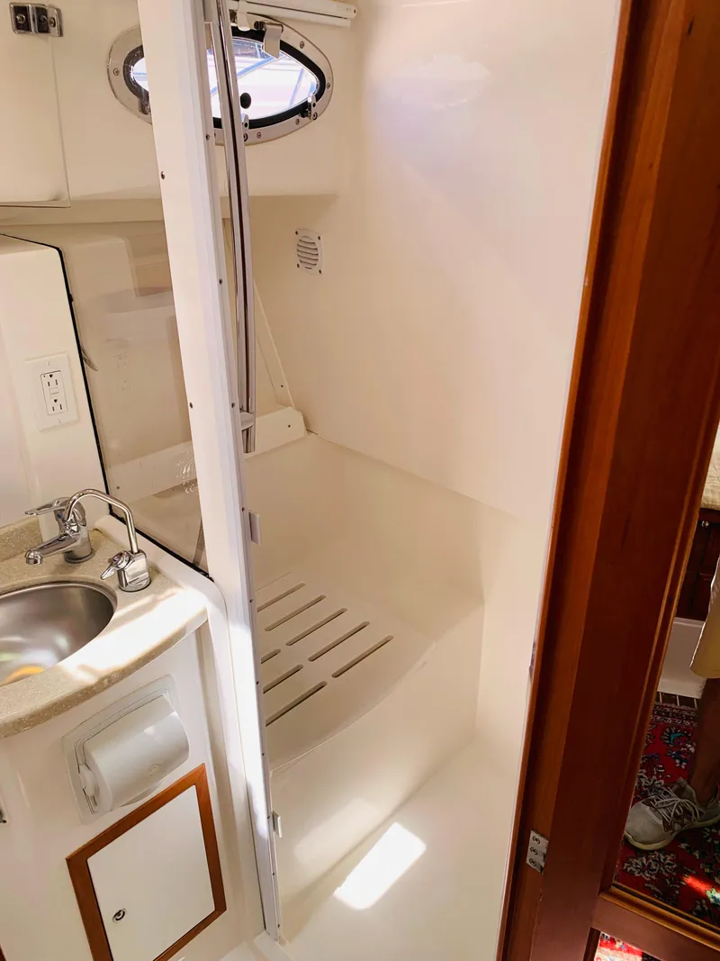 Slide: The Image of 2015 Back Cove 34 Express bathroom with sink, shower, and porthole window. - 26