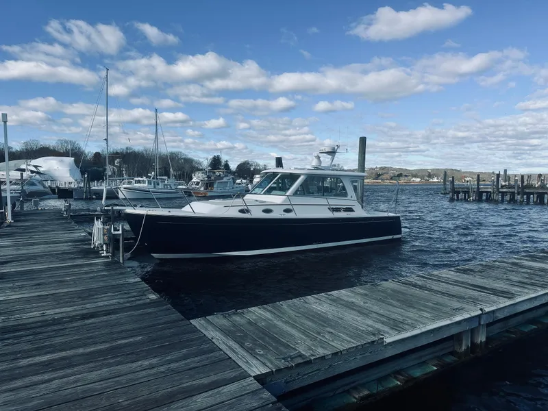 Slide: The Image of 2015 Back Cove 34 Express docked at a marina under a partly cloudy sky. - 4