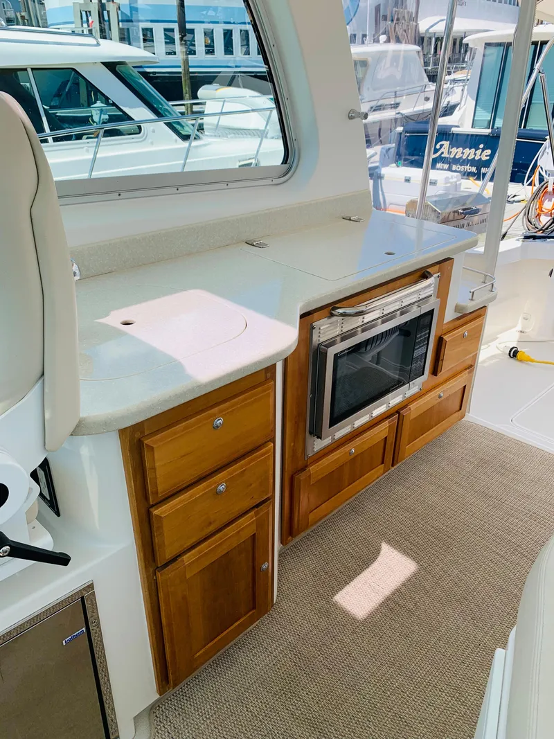 Slide: The Image of 2015 Back Cove 34 Express yacht interior with kitchenette and wooden cabinetry. - 40