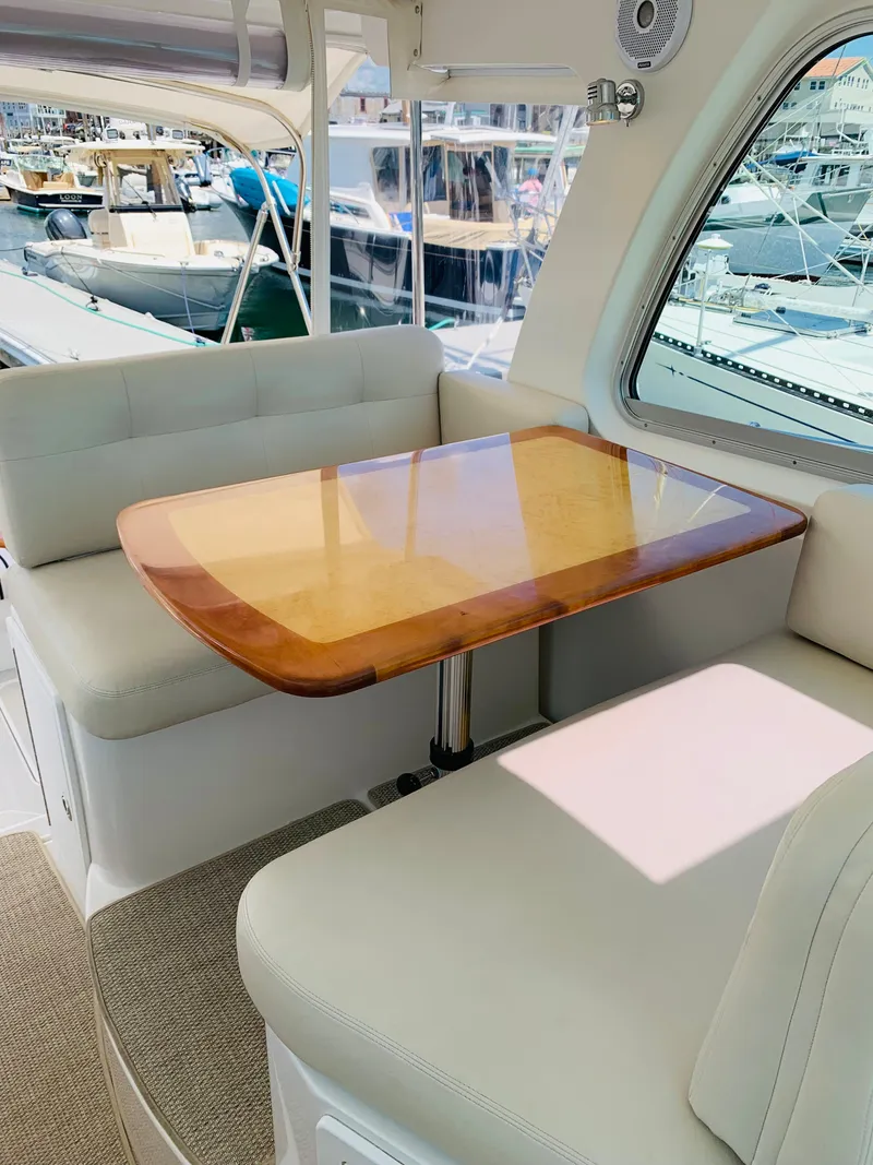 Slide: The Image of 2015 Back Cove 34 Express yacht interior with cushioned seating and wooden table. - 44