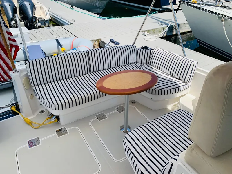 Slide: The Image of 2015 Back Cove 34 Express boat with striped seating and round table on deck. - 48
