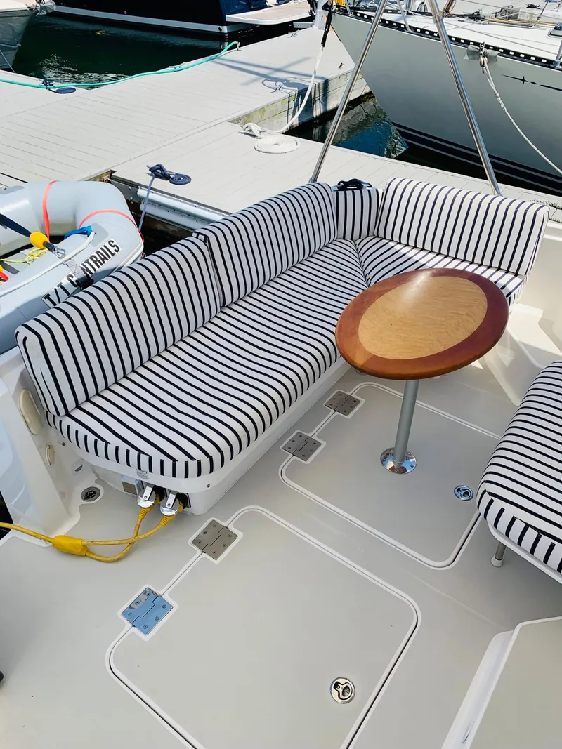Slide: The Image of 2015 Back Cove 34 Express boat with striped seating and round table on deck. - 49