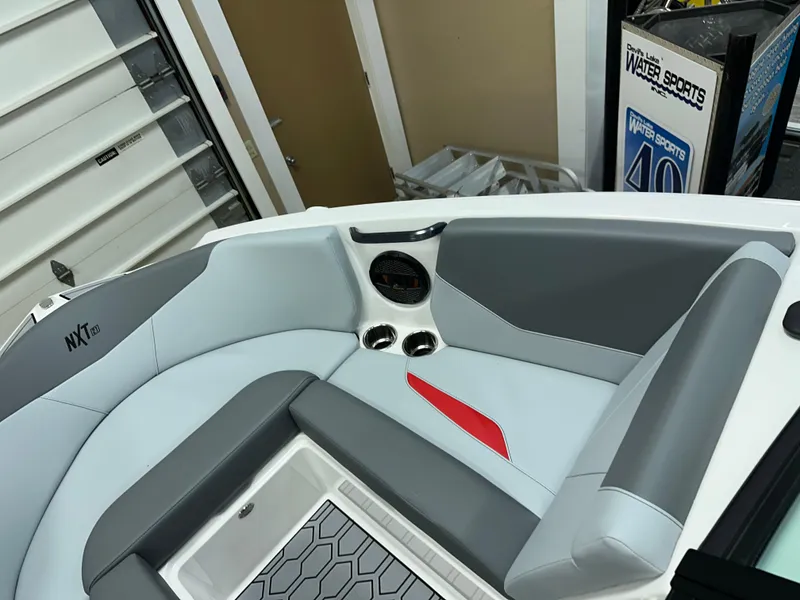 Slide: The Image of 2025 MasterCraft NXT21 boat interior with gray and red seating, cup holders, and modern design. - 15