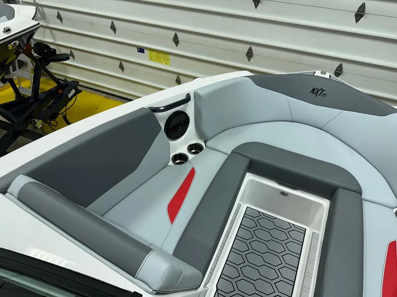 Slide: The Image of 2025 MasterCraft NXT21 boat interior with gray and red seating, speaker, and cup holders. - 16