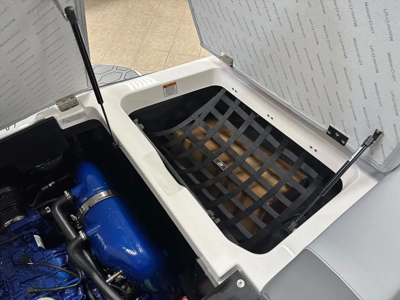 Slide: The Image of 2025 MasterCraft NXT21 engine compartment with storage netting and blue engine components. - 19