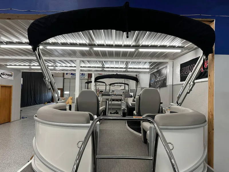 Slide: The Image of 2025 Barletta Cabrio 20QC pontoon boat in showroom with canopy and seating. - 19