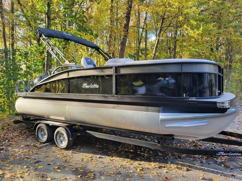 Slide: The Image of 2025 Barletta A20UC pontoon boat on trailer in wooded area. - 0