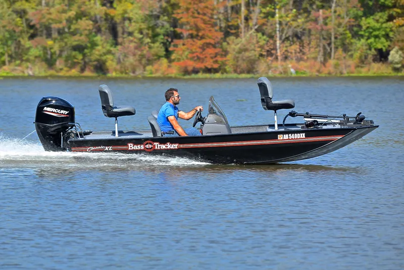 Slide: The Image of 2024 Bass Tracker Classic XL boat cruising on a lake with autumn trees in the background. - 3