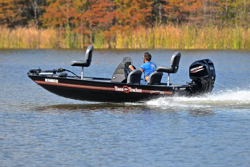 Slide: The Image of 2024 Bass Tracker Classic XL boat cruising on a lake with autumn foliage. - 4