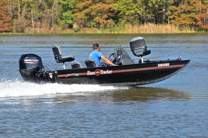 Slide: The Image of 2024 Bass Tracker Classic XL boat cruising on a lake with a Mercury engine. - 5