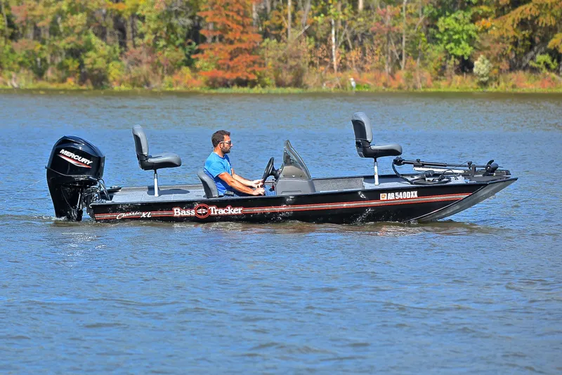 Slide: The Image of 2024 Bass Tracker Classic XL boat on a lake with a person driving. - 7