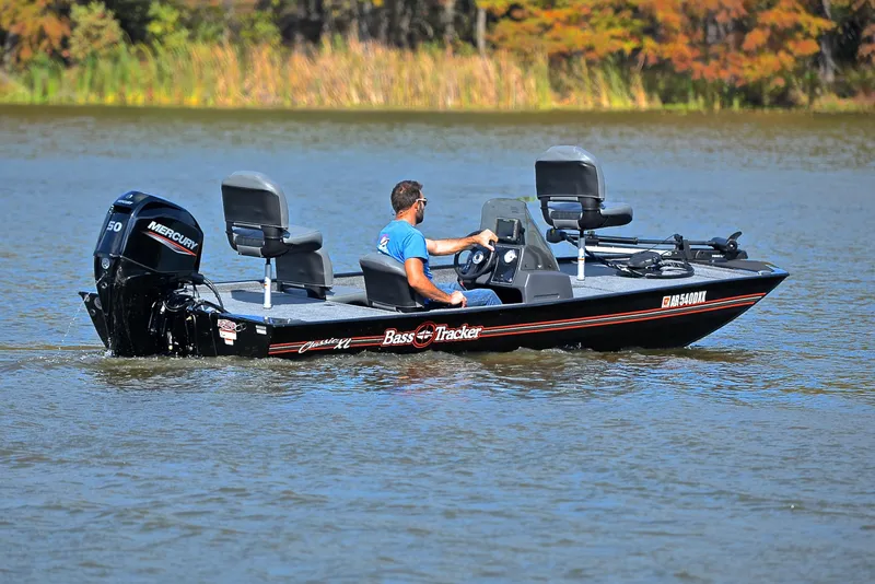 Slide: The Image of 2024 Bass Tracker Classic XL boat on a lake with a Mercury engine. - 8