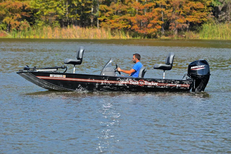 Slide: The Image of 2024 Bass Tracker Classic XL boat on a lake with a Mercury outboard motor. - 9