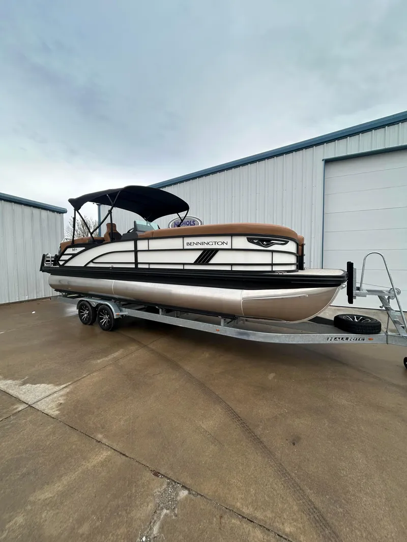 Slide: The Image of 2025 Bennington M26 pontoon boat on trailer, parked outside a warehouse. - 3