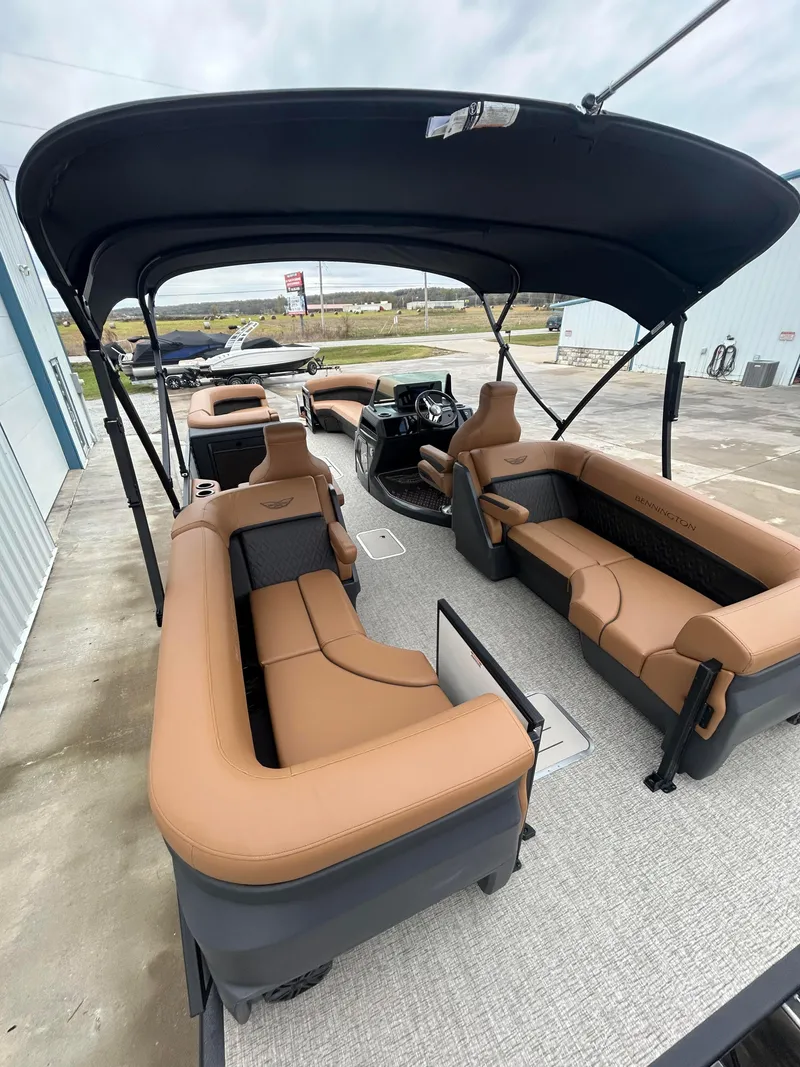 Slide: The Image of 2025 Bennington M26 boat interior with tan seating and canopy, docked outdoors. - 9