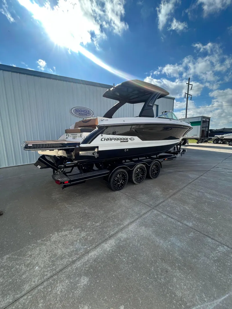 Slide: The Image of 2025 Chaparral 30 Surf boat on trailer, parked outdoors under a blue sky. - 2