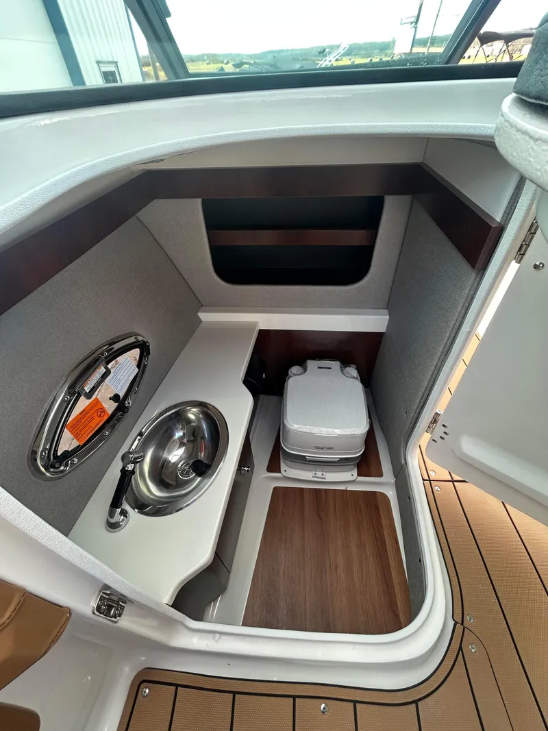 Slide: The Image of 2025 Chaparral 30 Surf boat interior with compact sink and portable toilet. - 9