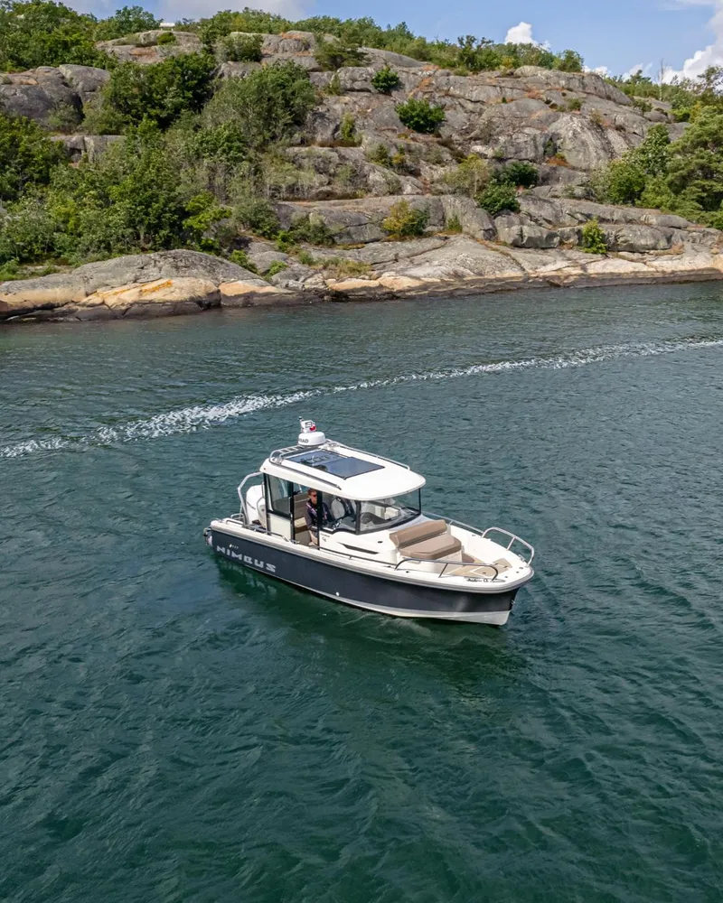 Slide: The Image of Nimbus C8 2025 boat cruising near rocky shoreline under clear sky. - 11