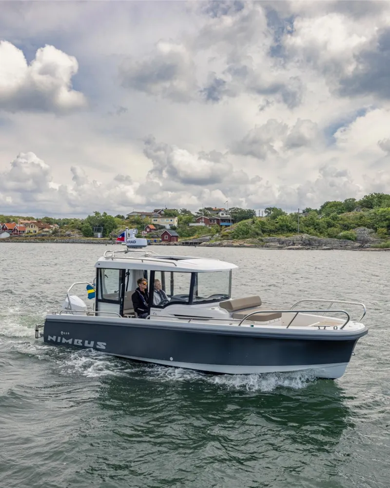 Slide: The Image of 2025 Nimbus C8 boat cruising on a scenic lake under cloudy skies. - 19