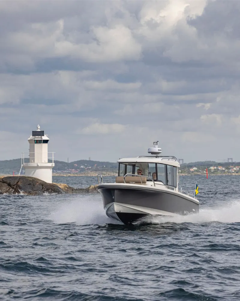 Slide: The Image of Nimbus C8 2025 boat cruising near a lighthouse on a cloudy day. - 3