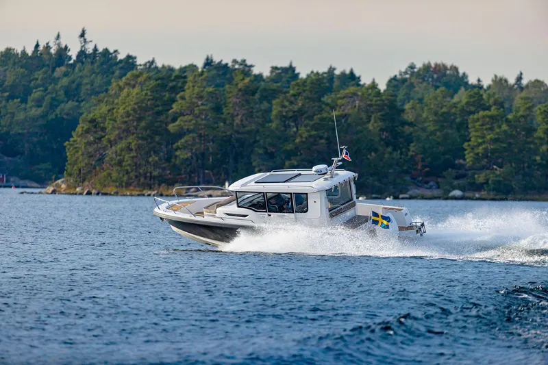 Slide: The Image of Nimbus C9 2025 boat cruising on a scenic lake with forested shoreline. - 26