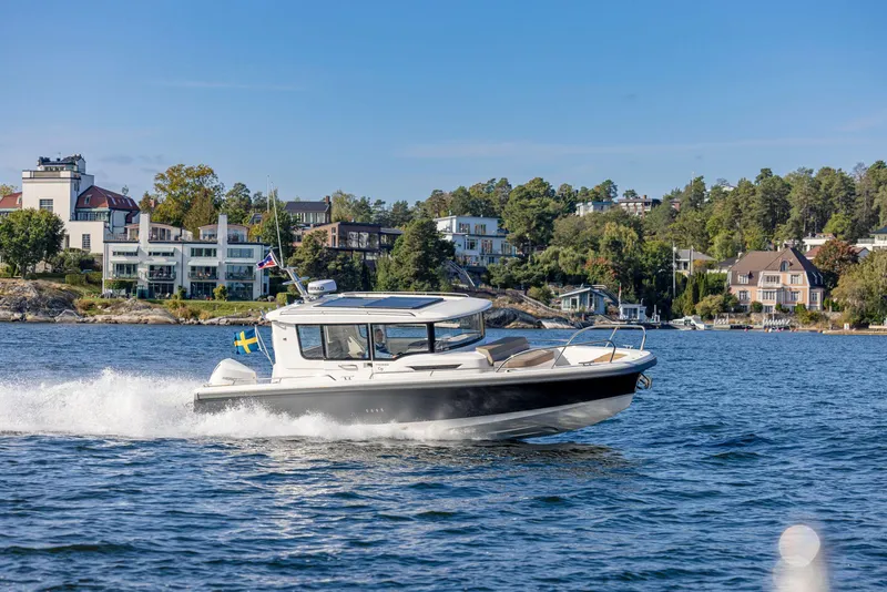 Slide: The Image of Nimbus C9 2025 boat cruising on a scenic lake with waterfront homes in the background. - 24