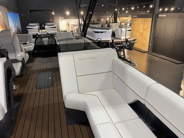 Slide: The Image of 2024 Manitou EXPLORE 24 MAX SGP boat interior with white seating and wood flooring. - 11