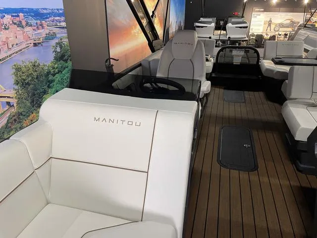 Slide: The Image of 2024 Manitou EXPLORE 24 MAX SGP boat interior with white seating and wood flooring. - 12